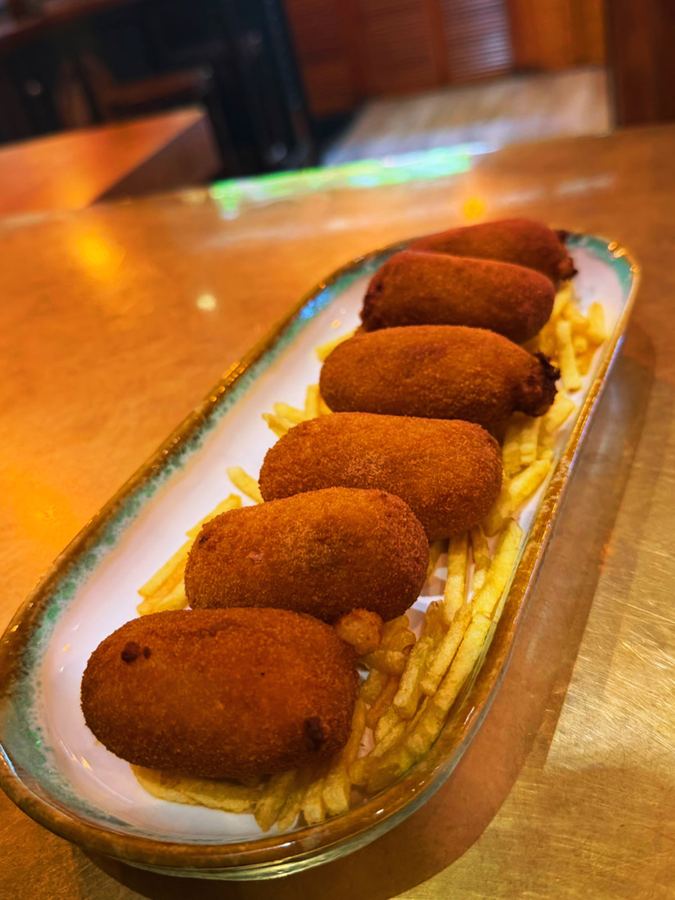Ración de croquetas sobre patatas paja