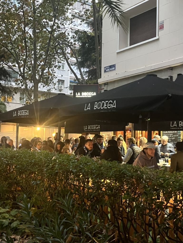 Terraza llena de gente al atardecer bajo las sombrillas de La Bodega